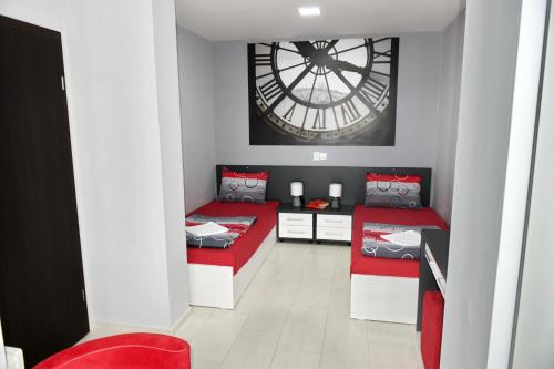 a room with two red beds and a large clock at Velestovo House in Ohrid