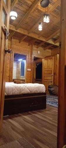 a bedroom with a large bed in a log cabin at wood house vattakanal in Kodaikānāl