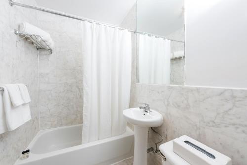 a white bathroom with a sink and a tub and a toilet at Park West Hotel in New York