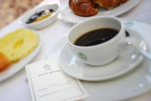 a cup of coffee on a table with plates of pastries at Hotel Greif in Lignano Sabbiadoro