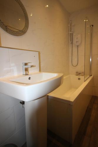 a bathroom with a sink and a bath tub at Cornerhouse Apartments 3 Sleeps 7 in Llandudno
