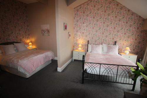 a bedroom with two beds and two lamps on tables at Cornerhouse Apartments 3 Sleeps 7 in Llandudno