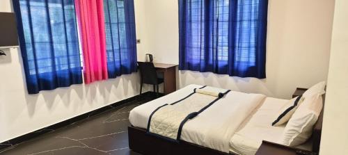 a bedroom with a bed with blue and red curtains at Green Lounge in Munnar