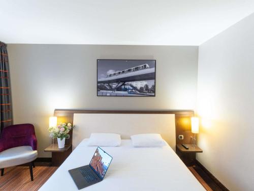 a bedroom with a bed with a laptop on it at Hotel Mercure Rennes Cesson in Cesson-Sévigné