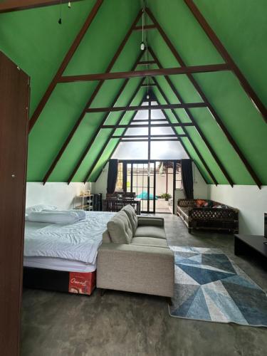 a green room with a bed and a couch at Mias Home in Sunggal