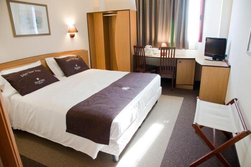 a hotel room with a large bed and a desk at Tulip Inn Turin South in Moncalieri