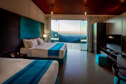 a hotel room with two beds and a balcony at The Pinnacle Ella Boutique Hotel and Spa in Ella