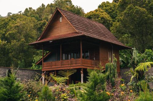 a small wooden house with a balcony in a forest at Munduk Seming Cottages in Munduk