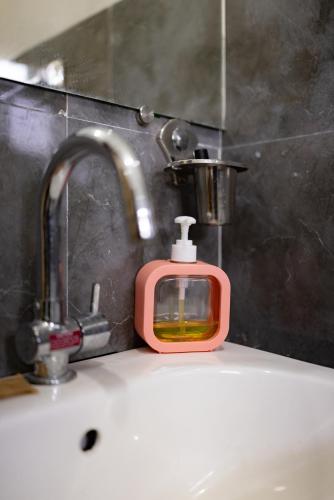 a bathroom sink with a soap dispenser next to a faucet at Bougain Villa in Madikeri