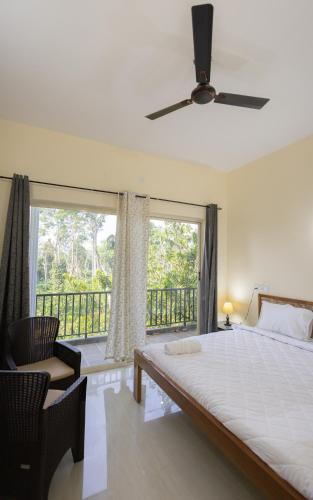 a bedroom with a large bed and a balcony at Bougain Villa in Madikeri