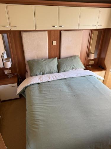 a large bed in a small room with cabinets at CJ Coastal Getaway #1 in Abergele