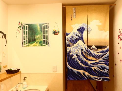 a bathroom with a painting of a wave on the wall at ホステル富士山 結 in Fujiyoshida