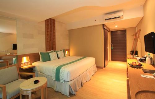 a bedroom with a bed and a chair and a television at Bedrock Hotel Kuta in Kuta