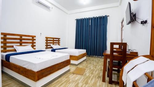 a bedroom with two beds and a desk and a television at OKI Nature Resort in Dambulla