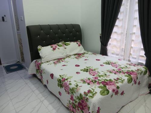 a bed with a floral comforter and pillows on it at Sri Biah Homestay in Kuala Berang