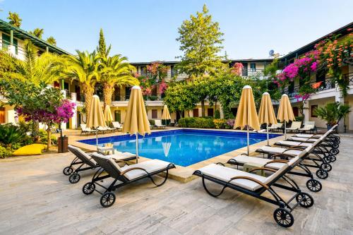 a group of lounge chairs and umbrellas next to a pool at Casa Blue Hotel All Inclusive in Bodrum City
