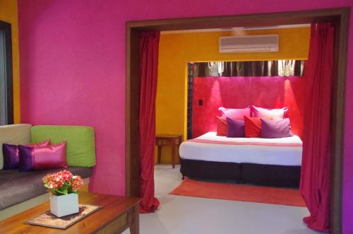a room with a bed with a mirror and a couch at Pink Flamingo Resort in Port Douglas