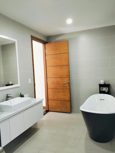 a bathroom with a tub and a sink and a door at Bin Bin Coastar Villa Hồ Tràm in Ho Tram