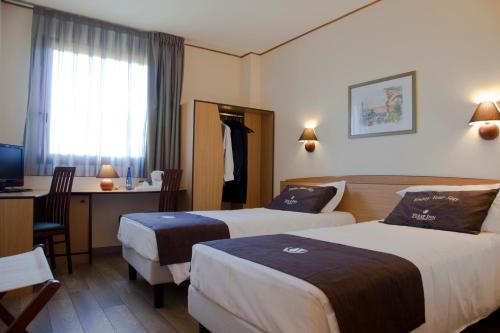 モンカリエーリにあるTulip Inn Turin Southのベッド2台とデスクが備わるホテルルームです。