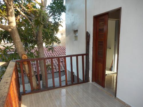 a balcony with a wooden door and a tree at Paracuru HolaOnda WaveHostel in Paracuru
