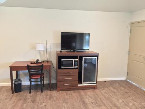 a room with a desk with a microwave and a television at Sterling Inn in Santa Clara