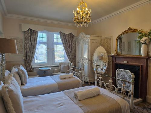a bedroom with two beds and a fireplace and a chandelier at The Old Tramhouse Self Catering Traditional Charming Apartments Located In The Heart Of Historic Stirling For Short-Long Stays In Stirling For Tourism & Events & Contractor Base Stays For Central Belt Area & Open To Book All Year Round in Stirling