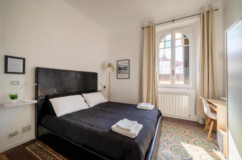 a bedroom with a black bed in a room with a window at Station 1 min - Monza Center, Milan - Wifi and AC in Monza