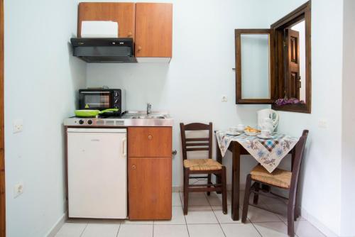 eine Küche mit einem Waschbecken und einem Tisch mit Stühlen in der Unterkunft Studios Leandros in Lákka