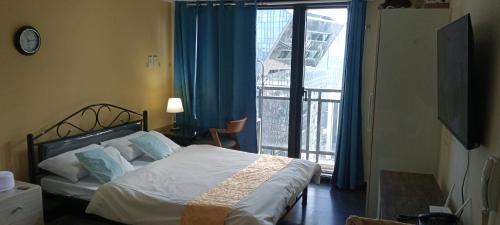a bedroom with a bed and a large window at Knightsbridge Residences with Free Pool, Sauna, Fast WiFi, Gym and Kitchen in Manila