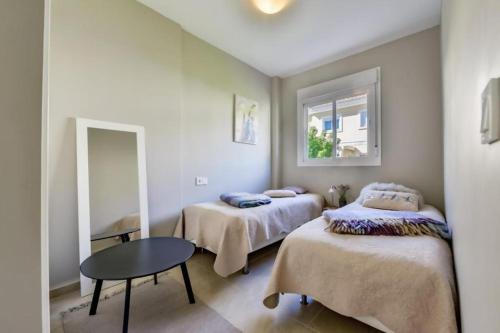 a room with two beds and a table and a window at Bungalow Montesol con Vistas al Mar y Montaña in Calpe