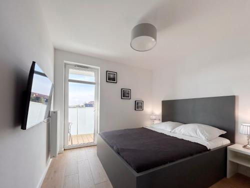 a bedroom with a large bed and a balcony at Posesja Kapitańska Apartament 18B 17 przy plaży in Grzybowo