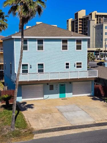 a blue house with a balcony and a palm tree at 126 E Pike home in South Padre Island