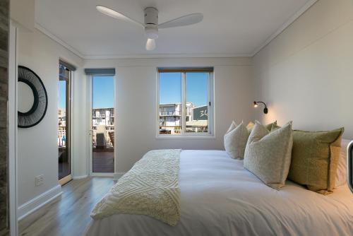 a white bedroom with a large bed with a ceiling fan at Knysna Waterfront, Stunning Views in Knysna