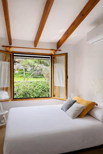 a bedroom with a large white bed and a window at Apartamento Ada a 2 minutos de la playa y con piscina! in Arenal d'en Castell