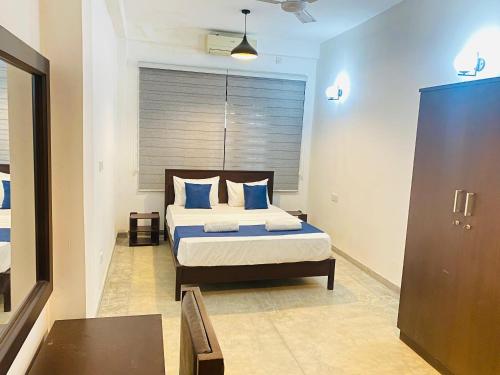 a bedroom with a bed with blue pillows at AYUBELLO hostel & suites in Ahungalla
