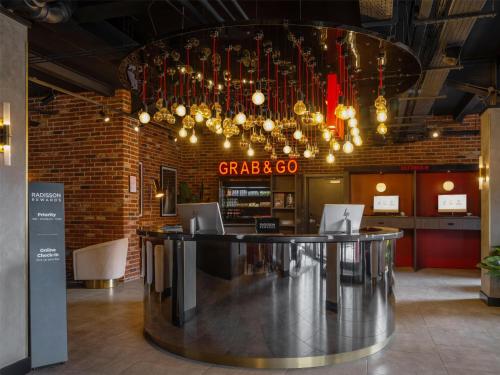 a bar in a restaurant with a chandelier at Radisson RED London Gatwick Airport in Crawley