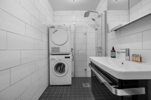 a white bathroom with a washing machine and a sink at Northstay - Skansegata Apartments, Apartment C l One-Bedroom in Tromsø