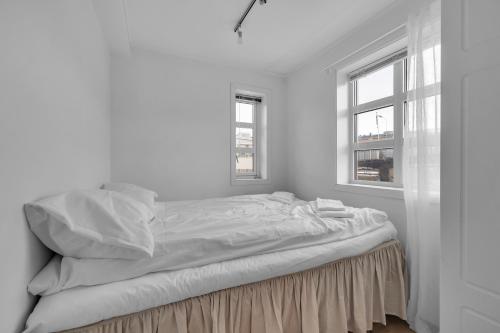 an unmade bed in a white room with two windows at Northstay - Skansegata Apartments, Apartment C l One-Bedroom in Tromsø