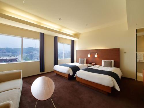 a hotel room with two beds and a couch at Oriental Hotel Hiroshima in Hiroshima