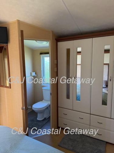 a bathroom with a toilet and some cabinets at CJ Coastal Getaway #1 in Abergele