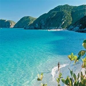 a person standing on a beach in the water at Pousada Mar Dos Anjos in Arraial do Cabo