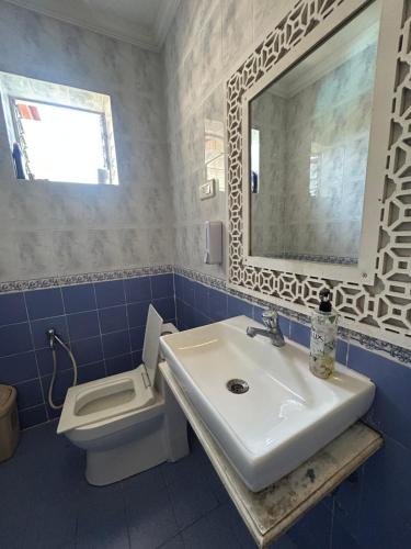 a bathroom with a sink and a toilet and a mirror at Lilly candolim apartment in Candolim