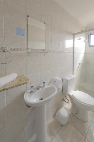 a white bathroom with a toilet and a sink at Hotel Montana Serra Negra in Serra Negra