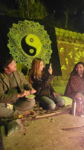 a group of people sitting on the ground at night at Vibe Hostel Naddi - Near Dal Lake in Dharamshala