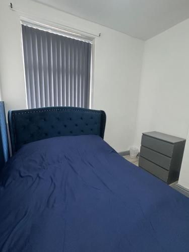 a bedroom with a blue bed and a window at Modern Apartment Bradford City Centre Self Check In in Bradford