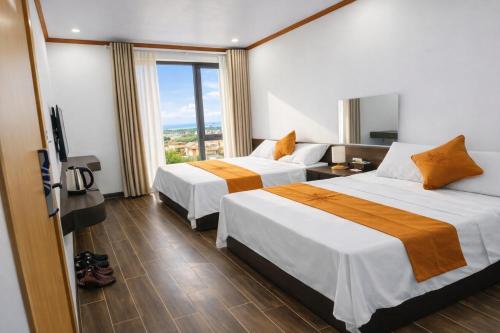 two beds in a hotel room with a window at Tiến Thành Hotel Nghệ An in Vinh