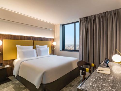 a hotel room with a large bed and a window at Pullman Paris Montparnasse in Paris