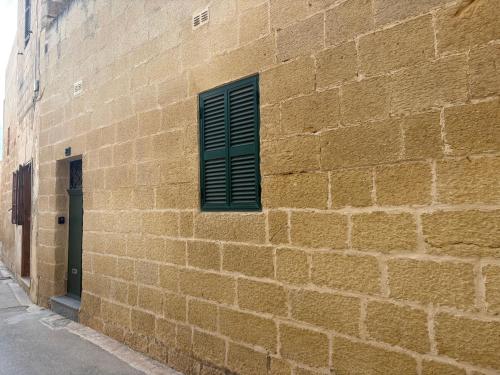 a brick wall with a green window on a building at Guesthouse 39 in Mqabba