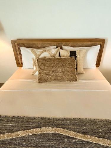 a bed with white pillows and a brown and white bedspread at La La Villas in Pulau Pototogat