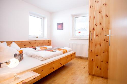 a bedroom with a wooden bed and two windows at Ferienhaus Alex in Wiesing